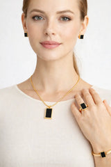 Woman wearing gold jewelry with black accents on a white background
